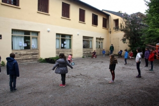 Imatge del pati de l&#039;escola Jordi Pere Cerdà de Sallagosa, situada a la banda administrativament francesa de la Cerdanya, on es veuen alumnes més grans esperant en punts distanciats i els petits jugant al darrere