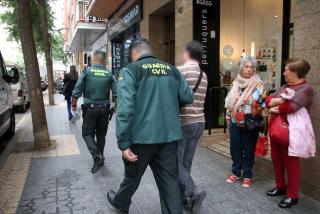 Dos policies de la Guàrdia Civil sortint amb un detingut en un dels registres fets a Tarragona durant l&#039;operatiu policial conjunt amb els Mossos d&#039;Esquadra