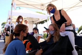 Imatge d’una perruquera pentinant el cabell d’una nena en la cinquena edició de la campanya “Deixa’t prendre el pèl” a Cambrils