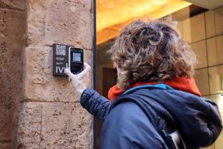 Una persona escanejant el QR de la nova placa instal·lada a l&#039;exterior de la joieria &#039;Personal&#039; de Tarragona i que forma part del projecte &#039;Empremtes del passat&#039;