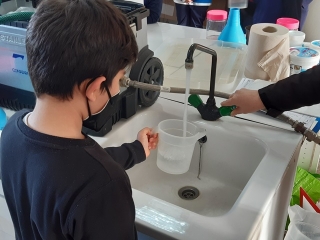 Un nen omple un recipient d&#039;aigua en un taller experimental